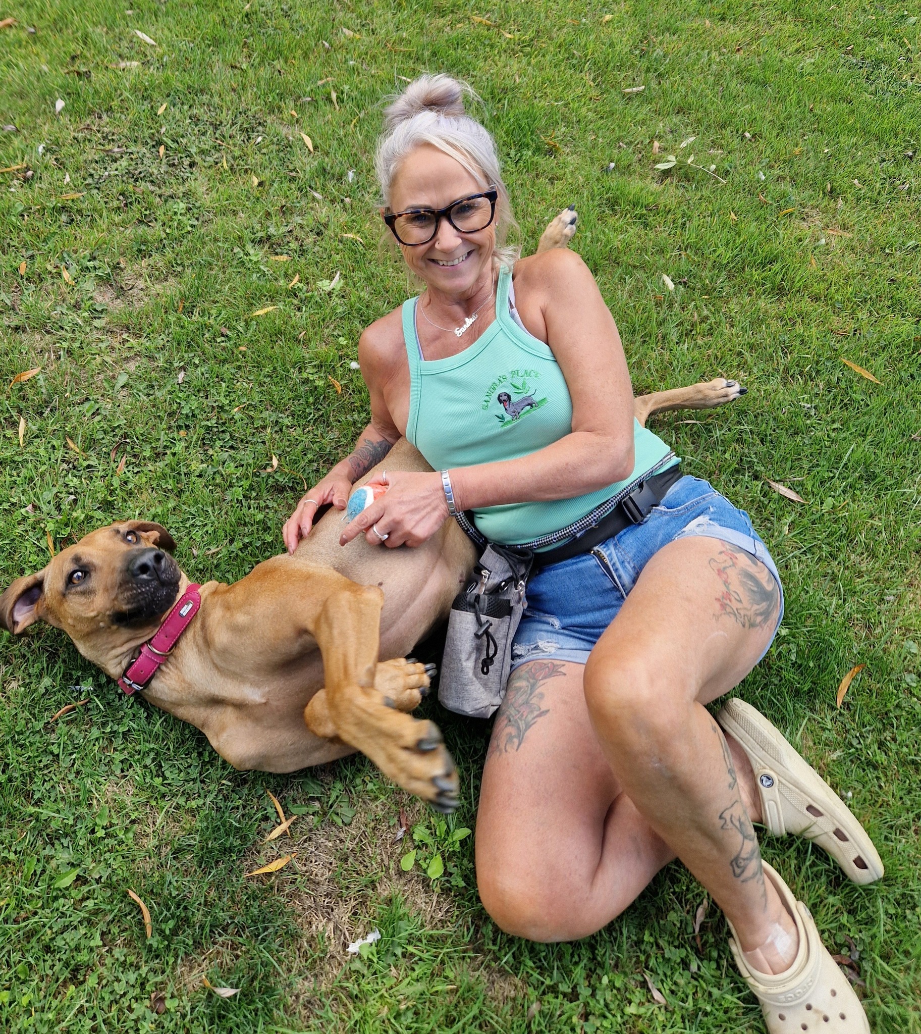 Sandra sitting on the grass with a happy dog